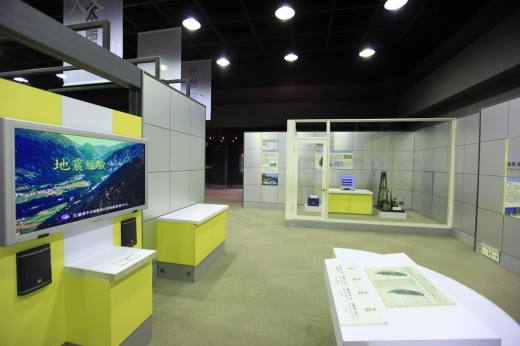從另一個角度來看地震展區，左邊牆面上有一台撥放地震介紹的螢幕，螢幕前方的平台上有關於臺灣地震介紹的簡介。後方另一個展示空間有一個測量地震的儀器。